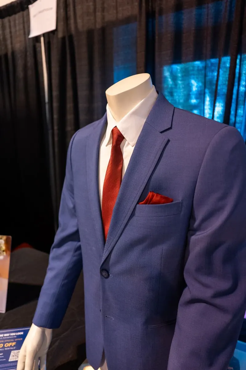 Headless mannequin in a blue suit with a red tie at a wedding vendor booth